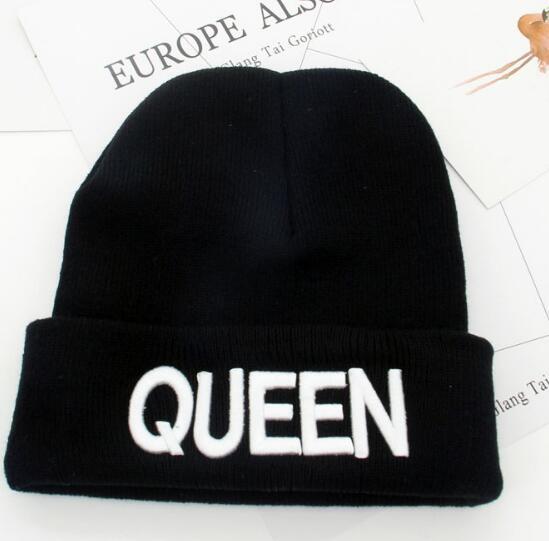 Black knit beanie hat with white embroidered text 'QUEEN' on folded brim