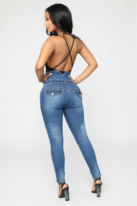 Woman in high-waisted blue skinny jeans and black strappy back top posing against white background
