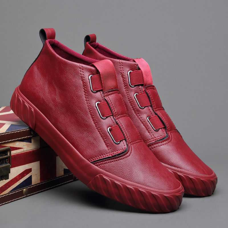 Pair of stylish red leather slip-on sneakers with elastic straps and rubber soles on a gray background