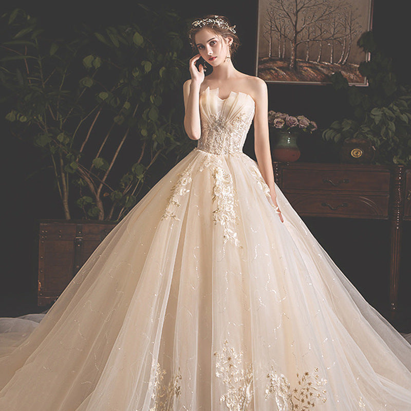 Elegant bride wearing strapless ball gown wedding dress with floral embroidery, indoor vintage setting