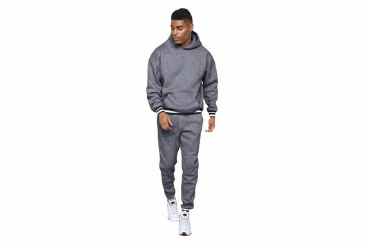 Man wearing gray hoodie and sweatpants with white sneakers on white background