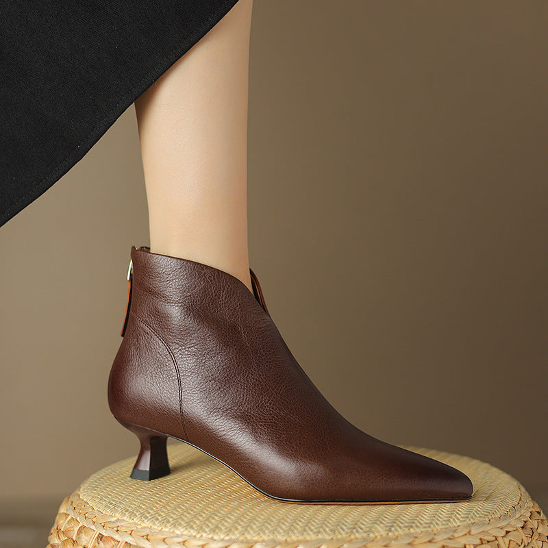 Woman wearing sleek brown leather ankle boots with kitten heels on woven mat