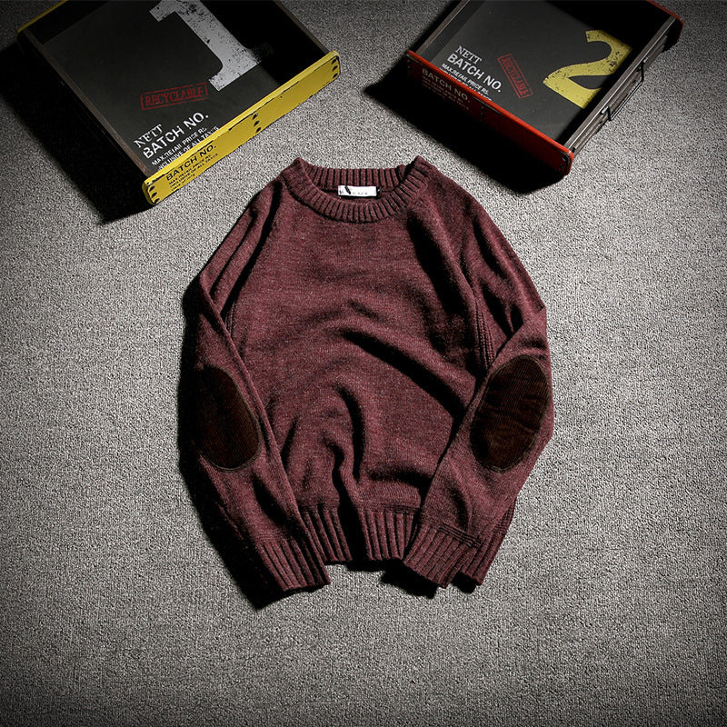 Maroon wool sweater with ribbed cuffs and elbow patches displayed on gray textured surface alongside numbered black and yellow boxes