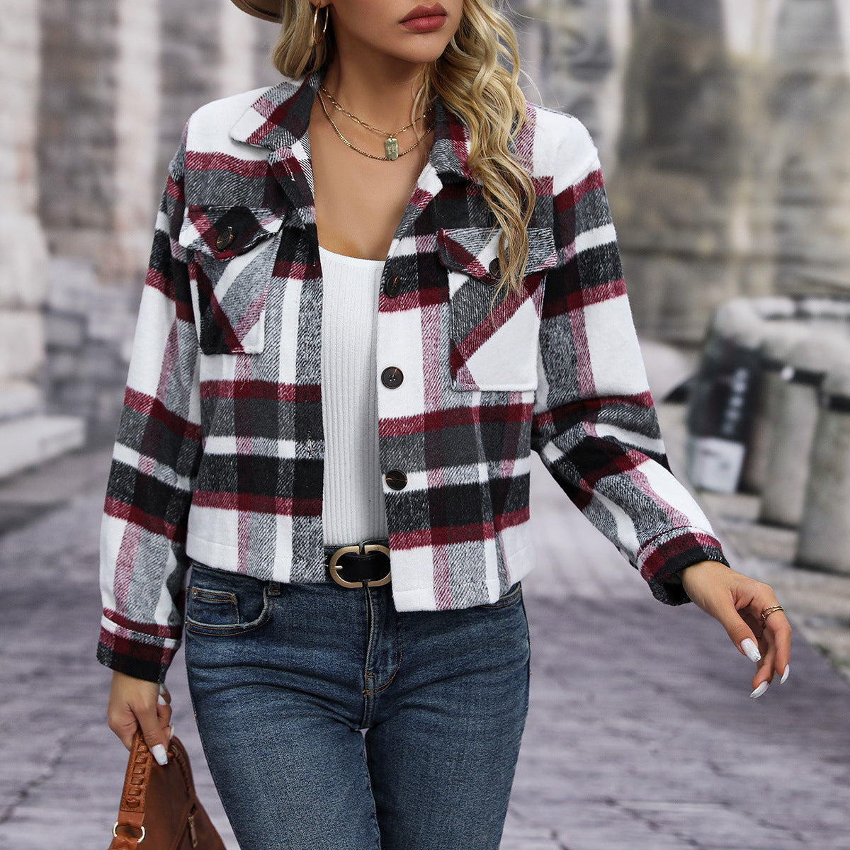 Woman wearing red black and white plaid buttoned jacket with front pockets and blue jeans