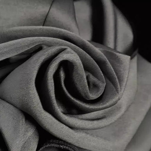 Close-up of soft gray fabric folded in a swirling pattern, highlighting texture and smoothness