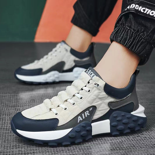 Modern air-cushioned sneakers with quilted beige, black, and dark blue design on textured floor