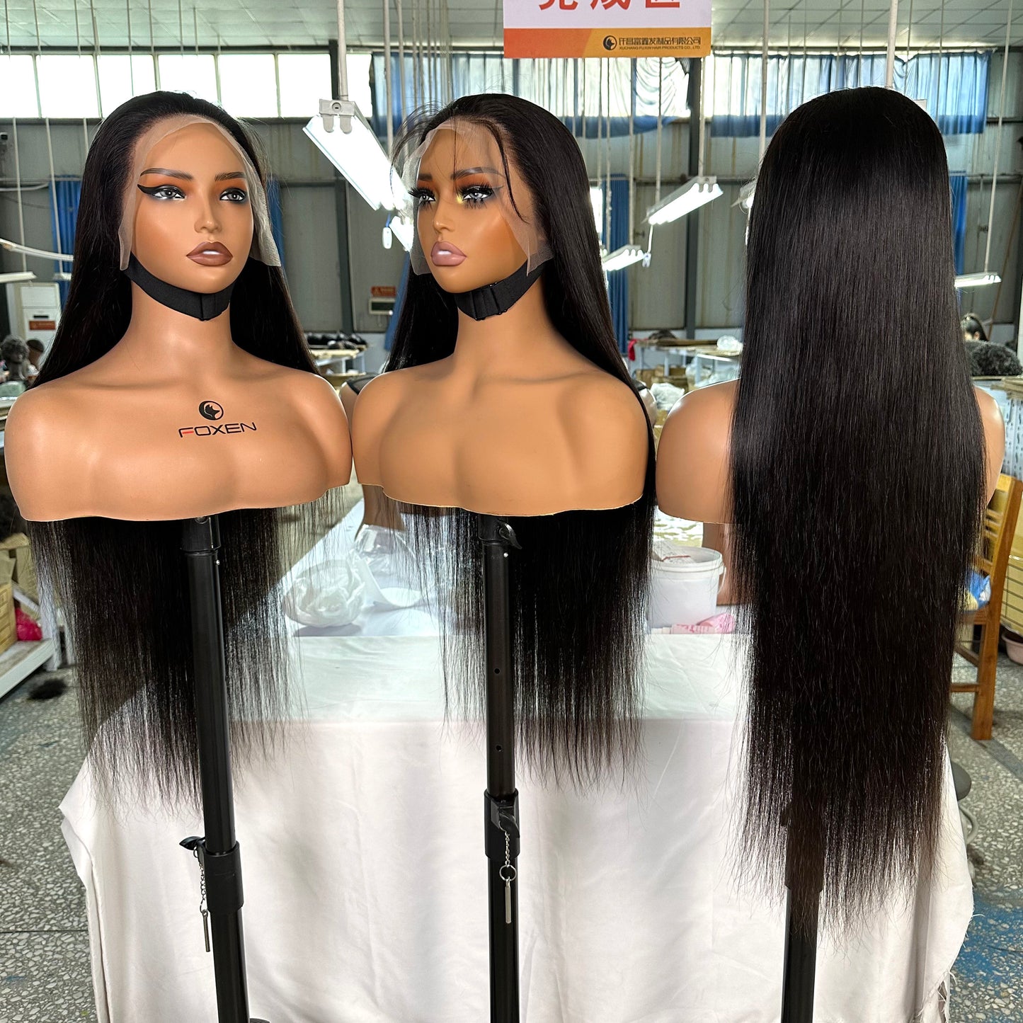 Three mannequin heads with long black straight lace front wigs displayed in a workshop setting