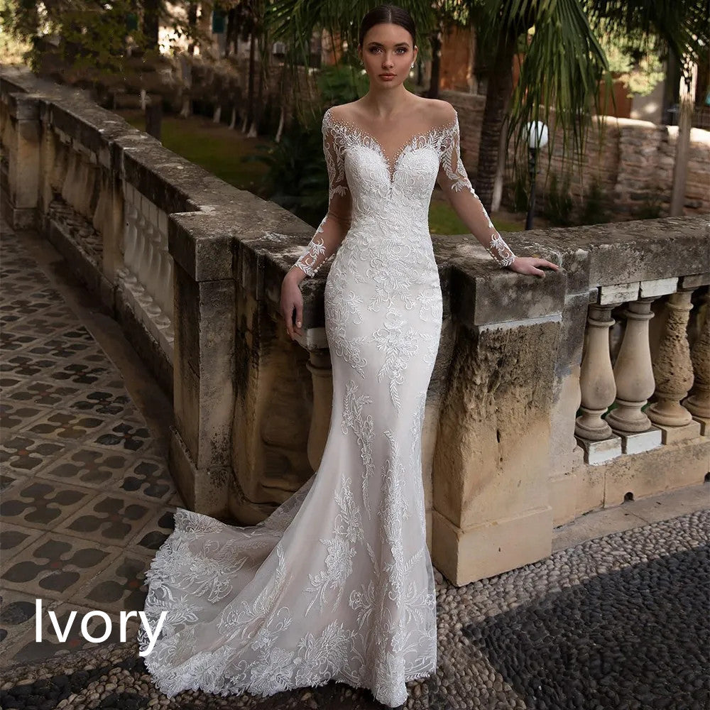 Bride in an ivory lace wedding dress with long sleeves posing by a stone balustrade in a garden