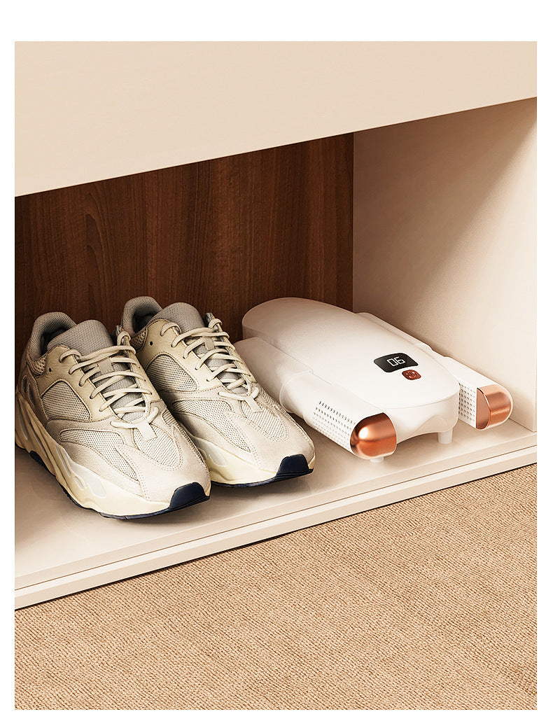 Pair of beige athletic shoes next to white shoe dryer with digital display inside wooden shelf