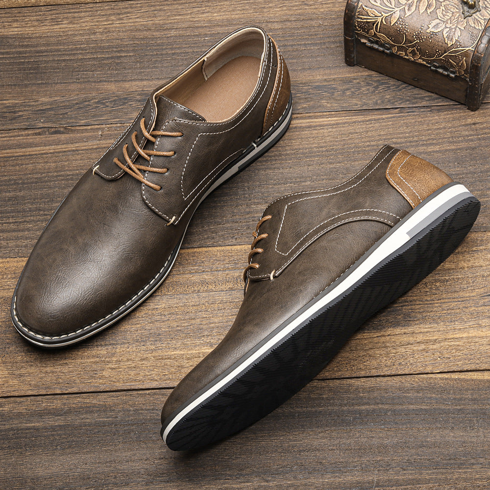 Brown leather casual lace-up shoes with white stitching on wooden surface