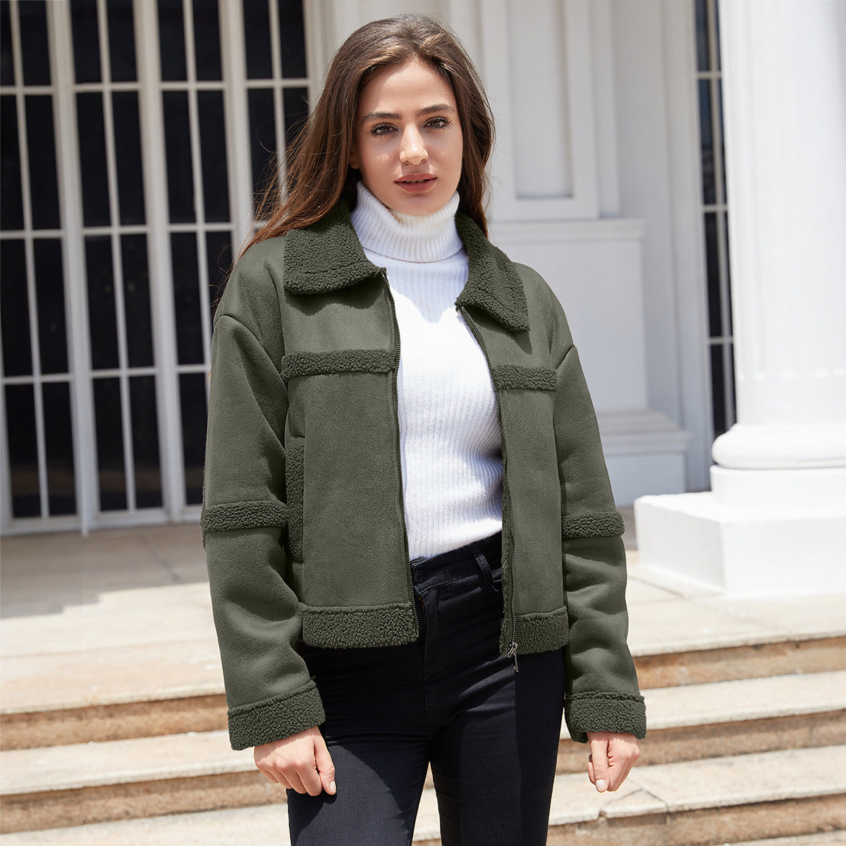 Woman wearing olive green sherpa jacket and white turtleneck sweater outdoors by white columns