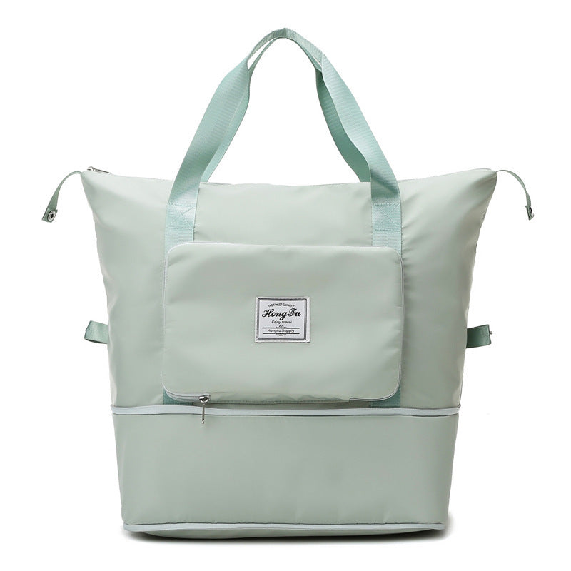 Light green dual-compartment tote bag with front zip pocket and sturdy handles on white background
