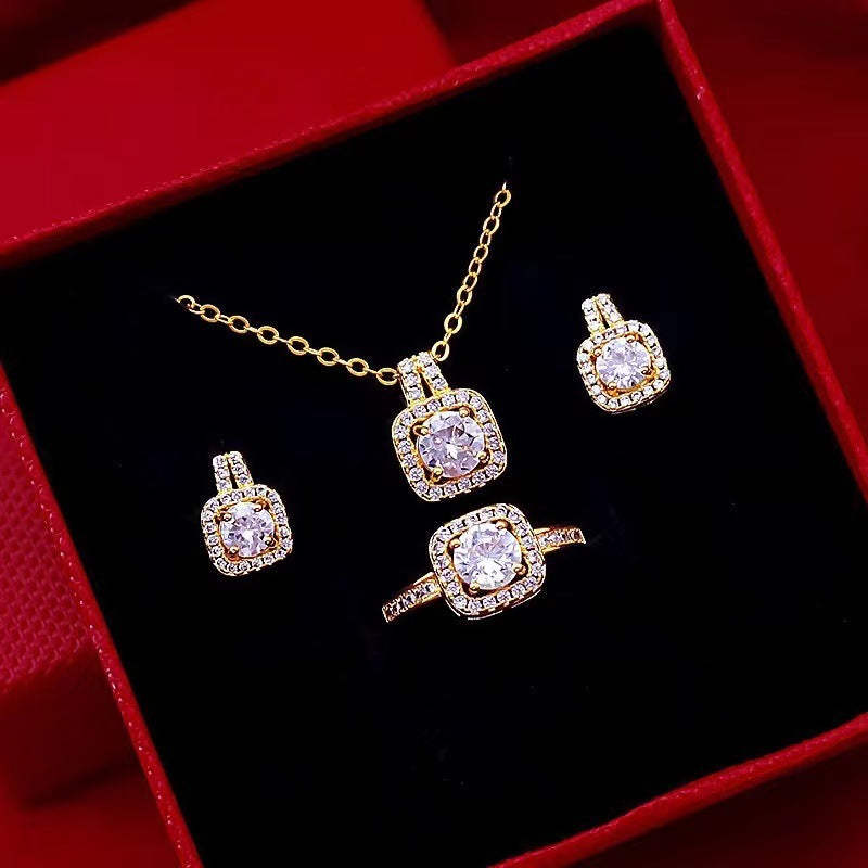 Gold jewelry set with diamond pendant necklace, ring, and earrings in red gift box