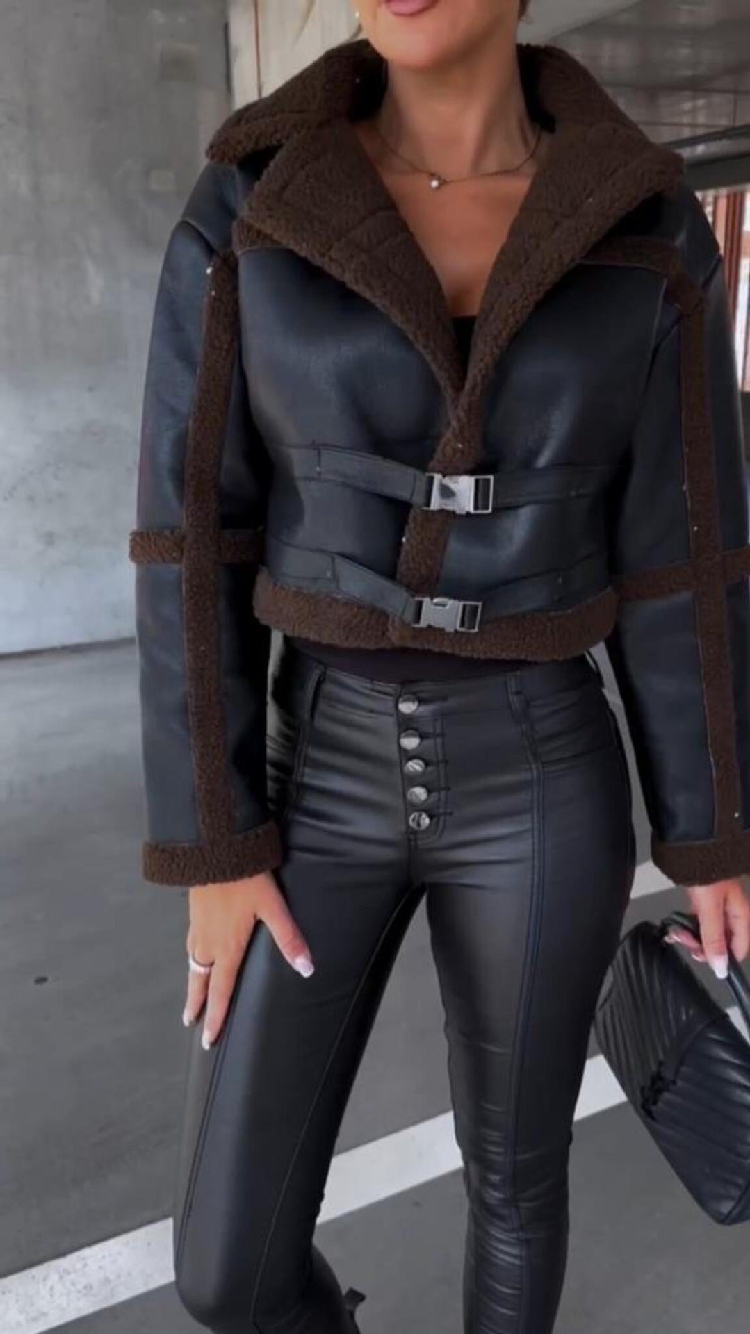 Woman wearing black leather jacket with brown shearling trim and high-waisted black leather pants