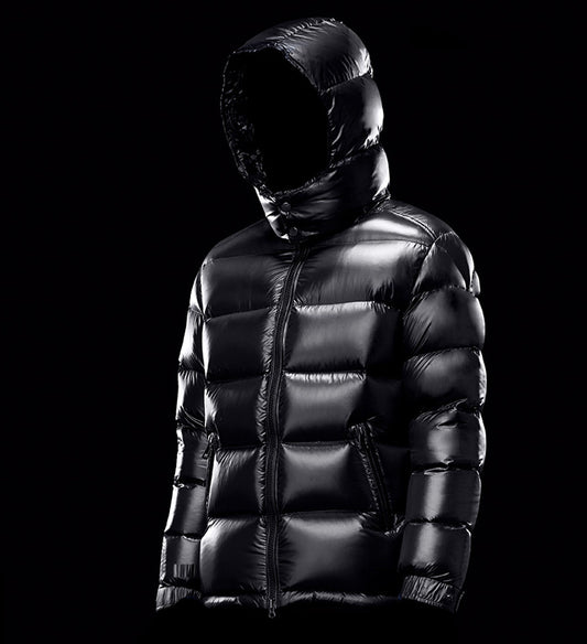 black shiny puffer jacket with hood on black background, quilted winter coat with front zipper