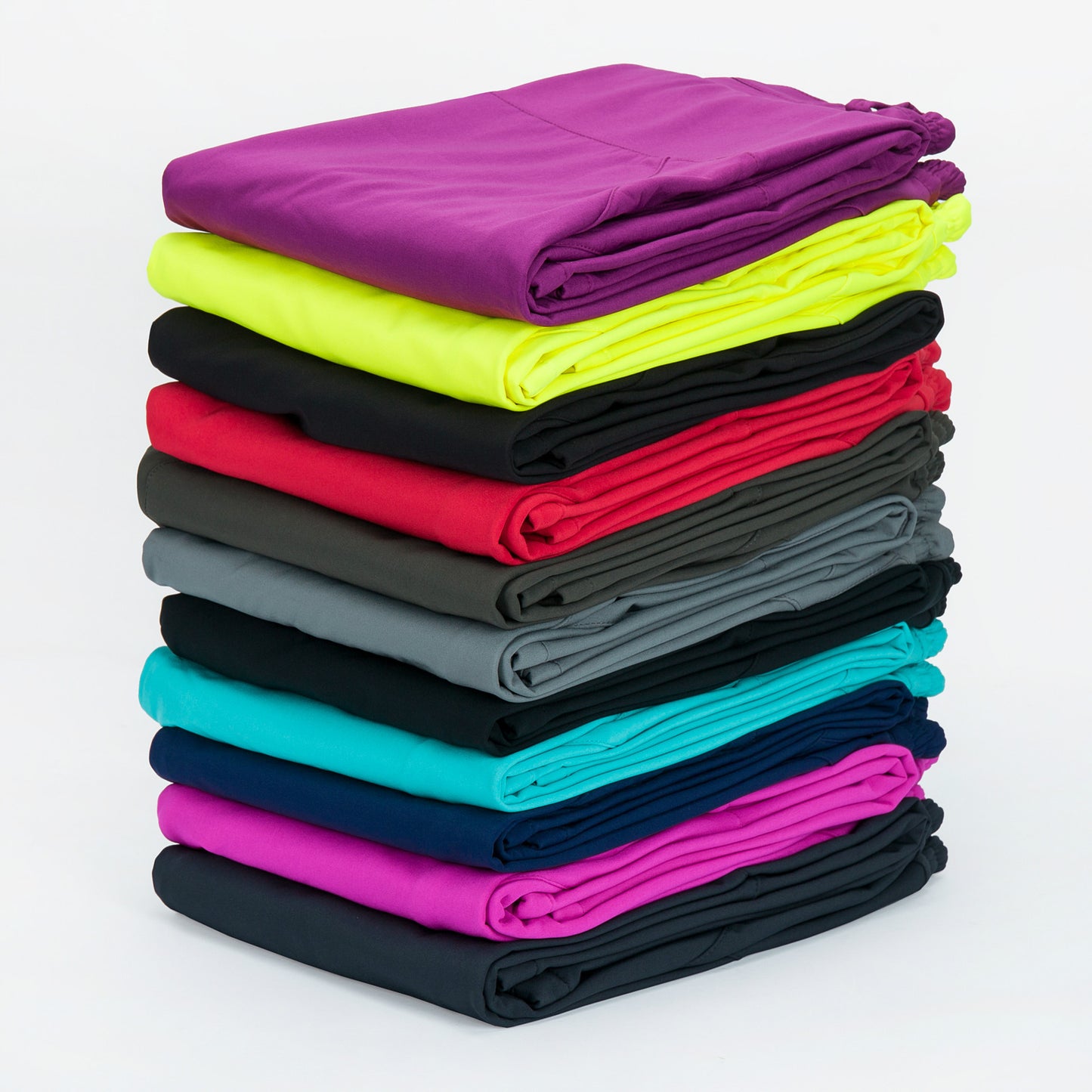 Stack of colorful folded leggings in purple, neon yellow, black, red, gray, teal, navy, and magenta on white background