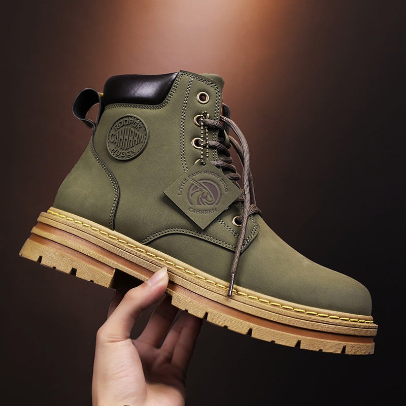 Hand holding olive green leather work boot with thick tan sole and CAHRHN logo tag