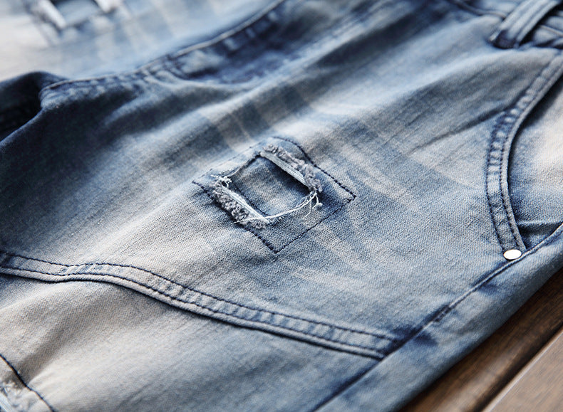 close-up of blue denim jeans with a small distressed square patch detail on wooden surface
