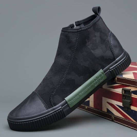 Black high-top sneaker with camouflage pattern and green logo plate on sole, displayed on Union Jack box