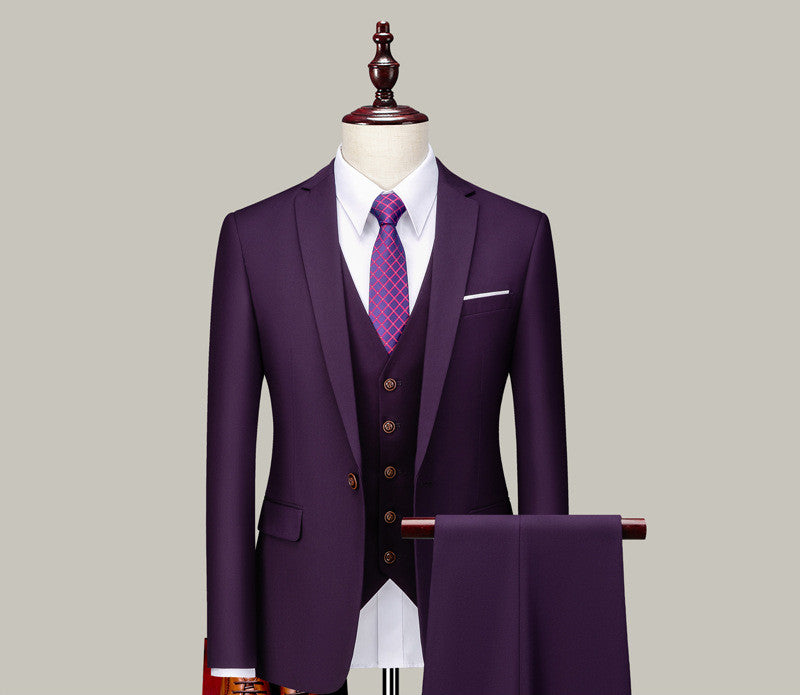 Purple three-piece men's suit with vest, white shirt, and patterned tie on mannequin with hanging trousers