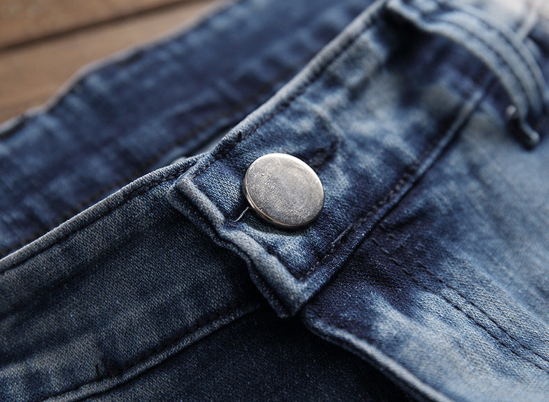 Close-up of metal button on blue denim jeans with detailed stitching