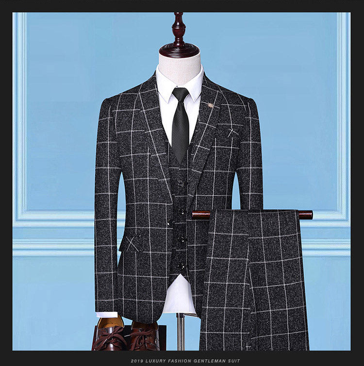 Men's luxury three-piece black suit with white windowpane pattern, black tie, and brown leather shoes