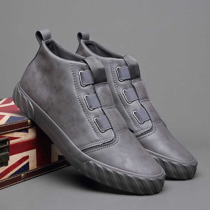Pair of modern gray slip-on casual shoes with elastic bands and rubber soles on a Union Jack box