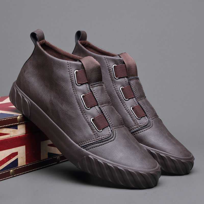 Pair of brown slip-on leather casual shoes with elastic bands and rubber soles on a Union Jack box