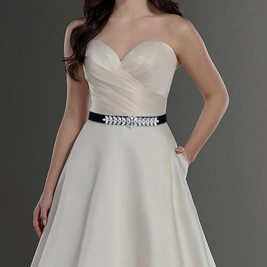 Strapless white wedding dress with pleated bodice and black belt featuring crystal embellishments
