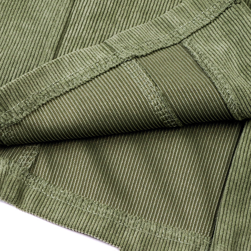 Close-up of olive green corduroy fabric showing ribbed texture and detailed stitching