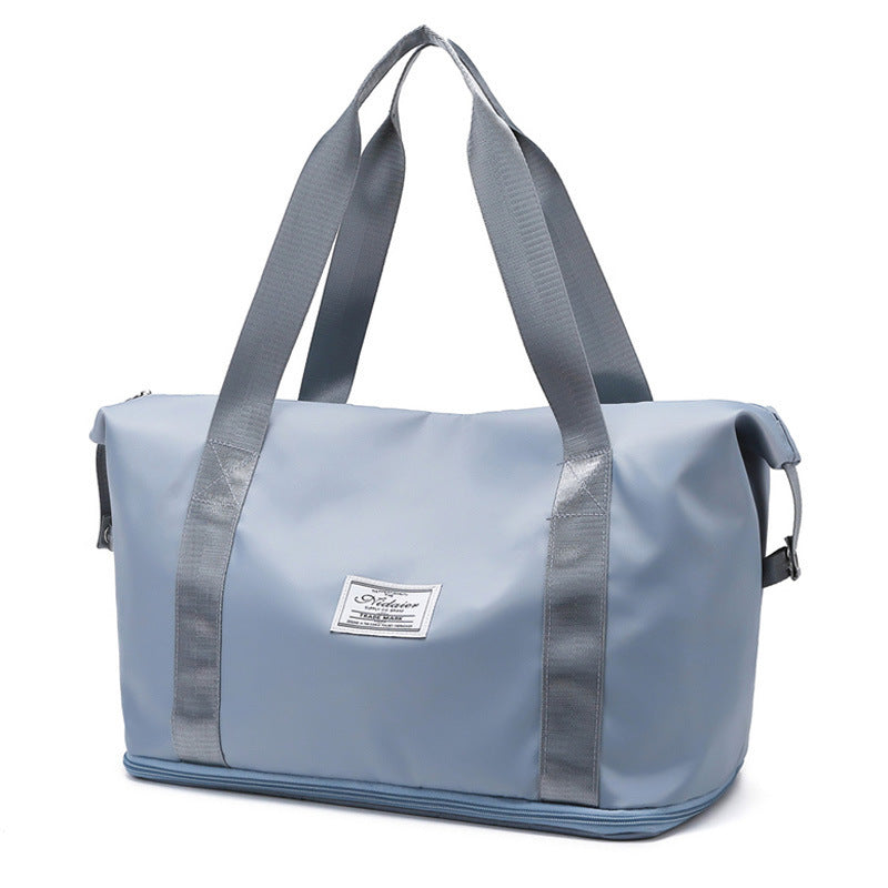 Light blue duffel bag with grey straps and a front label, studio white background