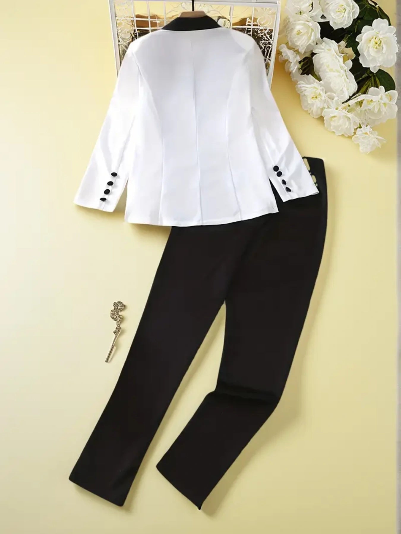 Black and white two-piece women's suit set with button-front blazer and straight-leg pants on yellow background