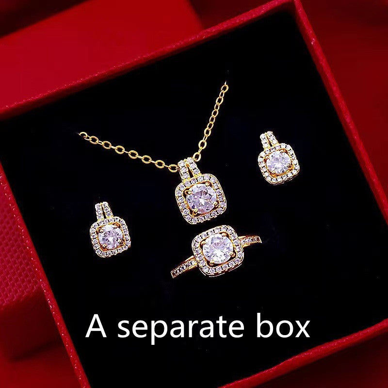 Gold jewelry set with diamond-like stones including necklace, ring, and earrings in red box