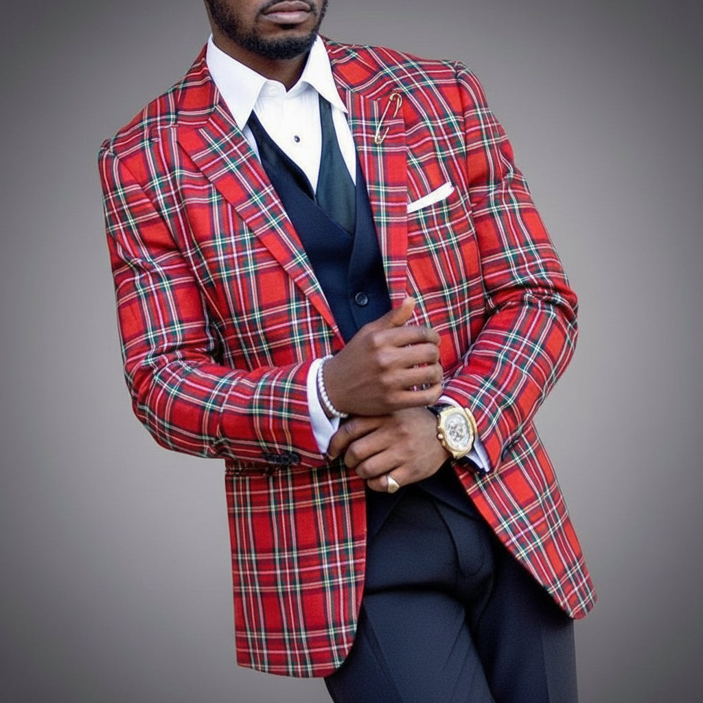 Man wearing red plaid blazer, white shirt, black vest, and gold watch on gray background