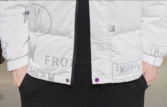 Close-up of person wearing white jacket with gray text and black pants, hands in pockets