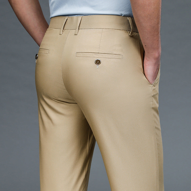 Close-up of man wearing beige dress pants with buttoned back pockets and hands in side pockets