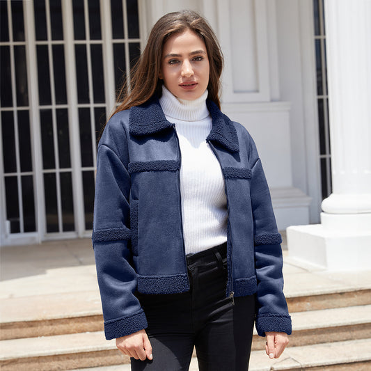 Woman wearing navy blue shearling jacket and white turtleneck sweater standing outdoors