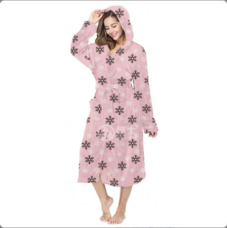 Woman wearing pink hooded bathrobe with black and white snowflake pattern, standing barefoot