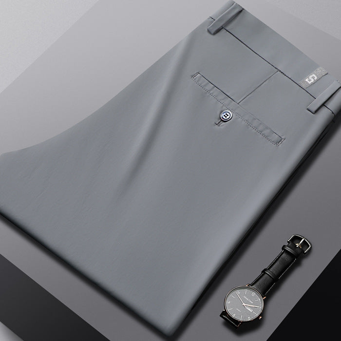 Folded gray dress pants with back pocket and black leather strap wristwatch on gray background