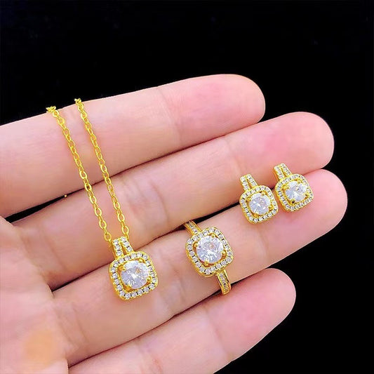Gold jewelry set with sparkling square-cut diamond pendant necklace, ring, and earrings on hand