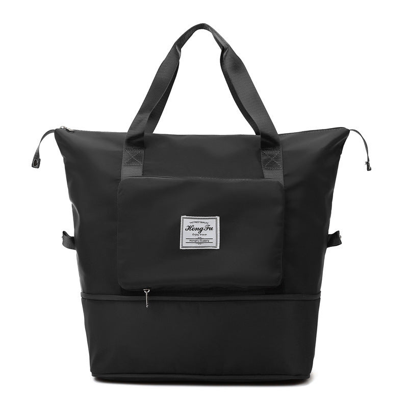 Black large tote bag with dual handles, front zip pocket, and bottom compartment zipper
