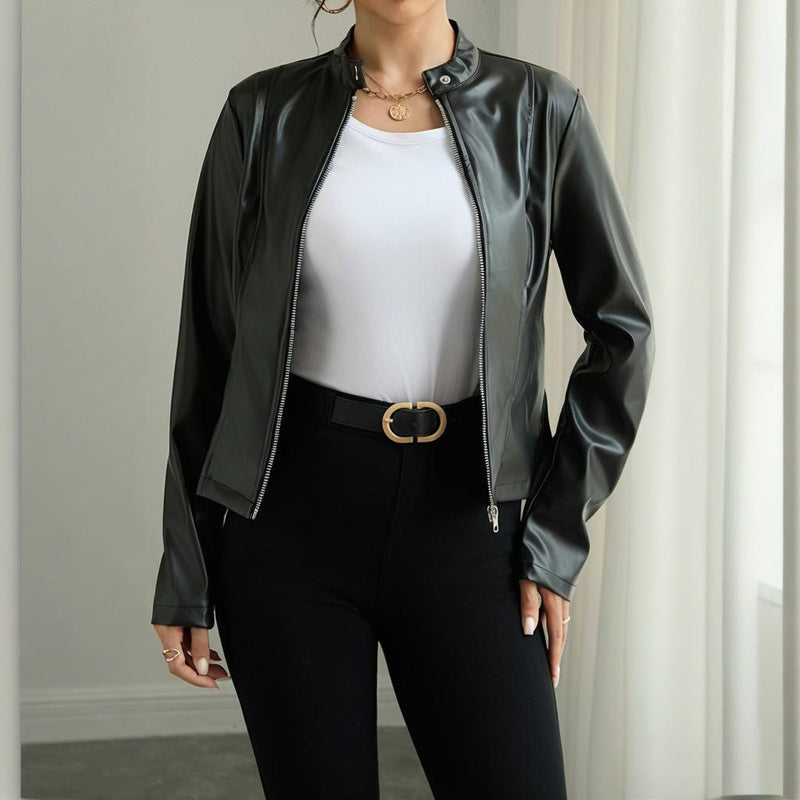 Woman wearing black faux leather zip-up jacket over white top with black pants and gold buckle belt