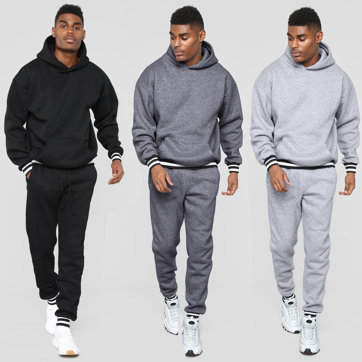 Man modeling black, dark gray, and light gray hooded sweatshirts and jogger pants with striped cuffs and white sneakers