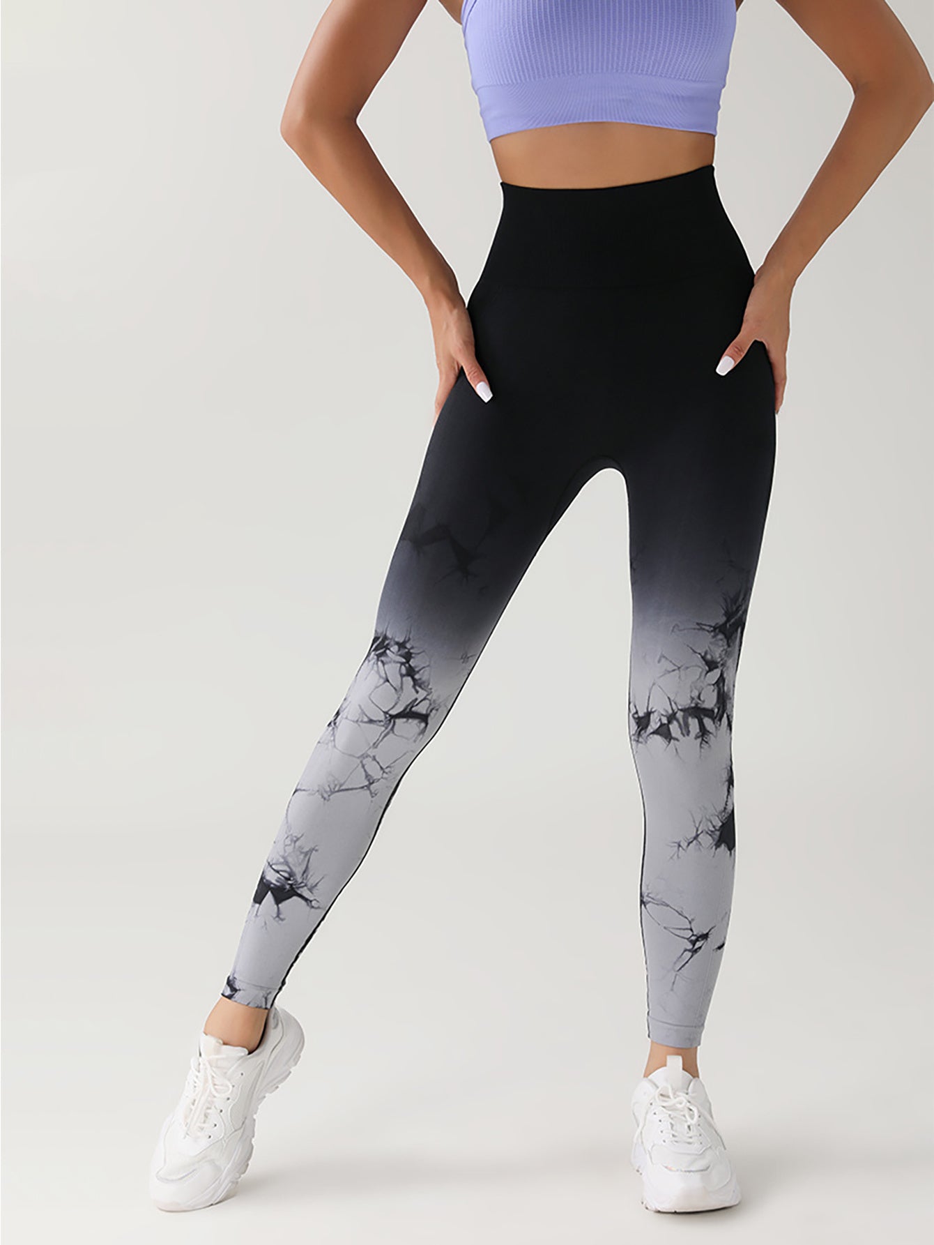Woman wearing black to gray ombre marble print leggings and white sneakers with lilac sports bra