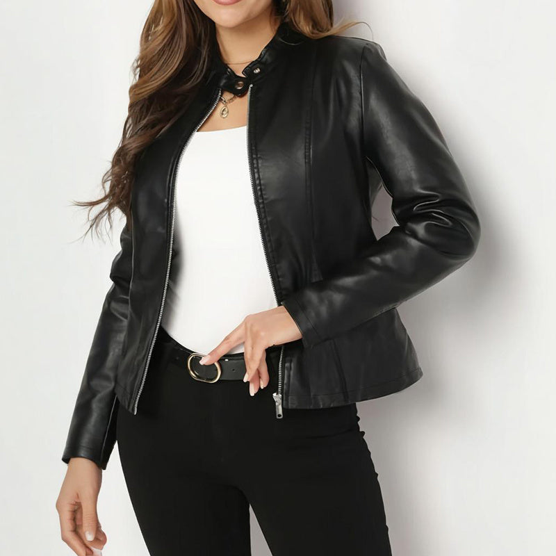 Woman wearing a black leather jacket, white top, black pants, and black belt with gold buckle