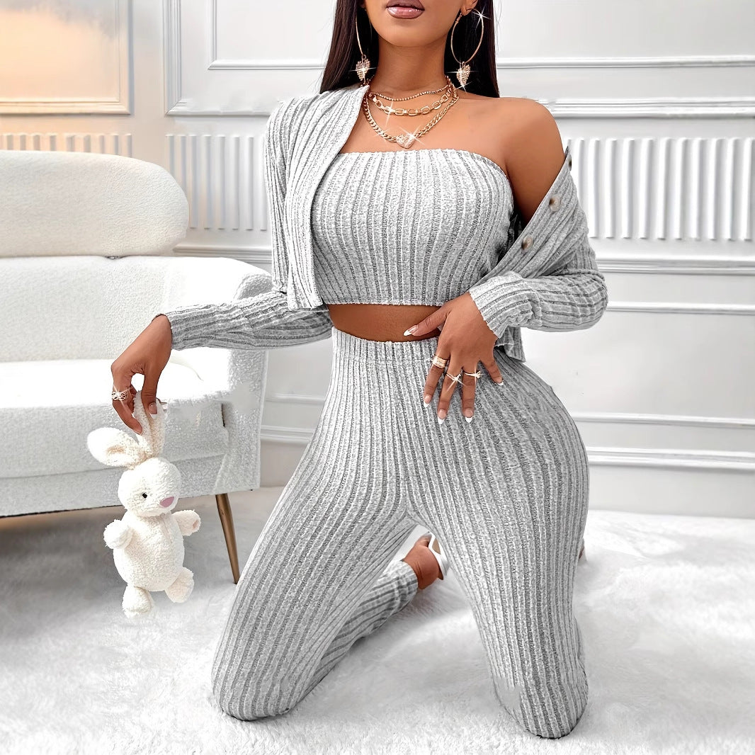 Woman in gray ribbed knit loungewear holding a plush white bunny in a modern white room