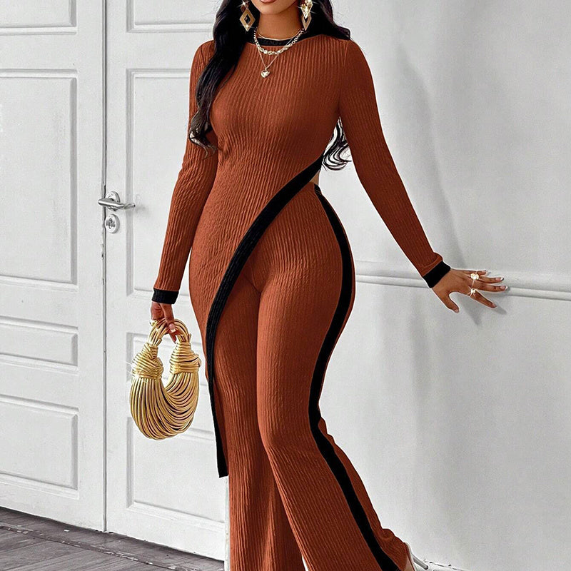 Woman wearing rust-orange ribbed jumpsuit with black stripes holding gold handbag by white doors