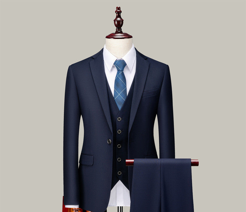 Navy blue three-piece suit with white dress shirt and blue plaid tie on mannequin with matching trousers