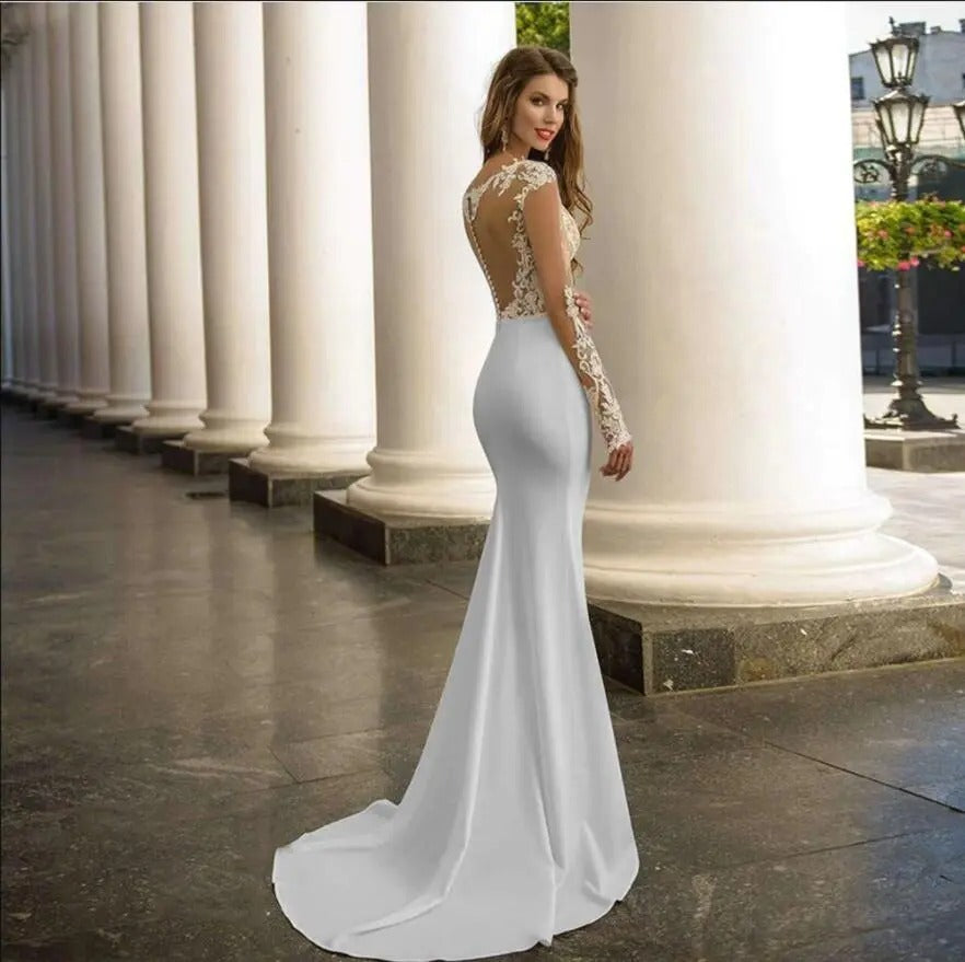 Woman wearing white lace long sleeve backless wedding dress standing by large classical columns