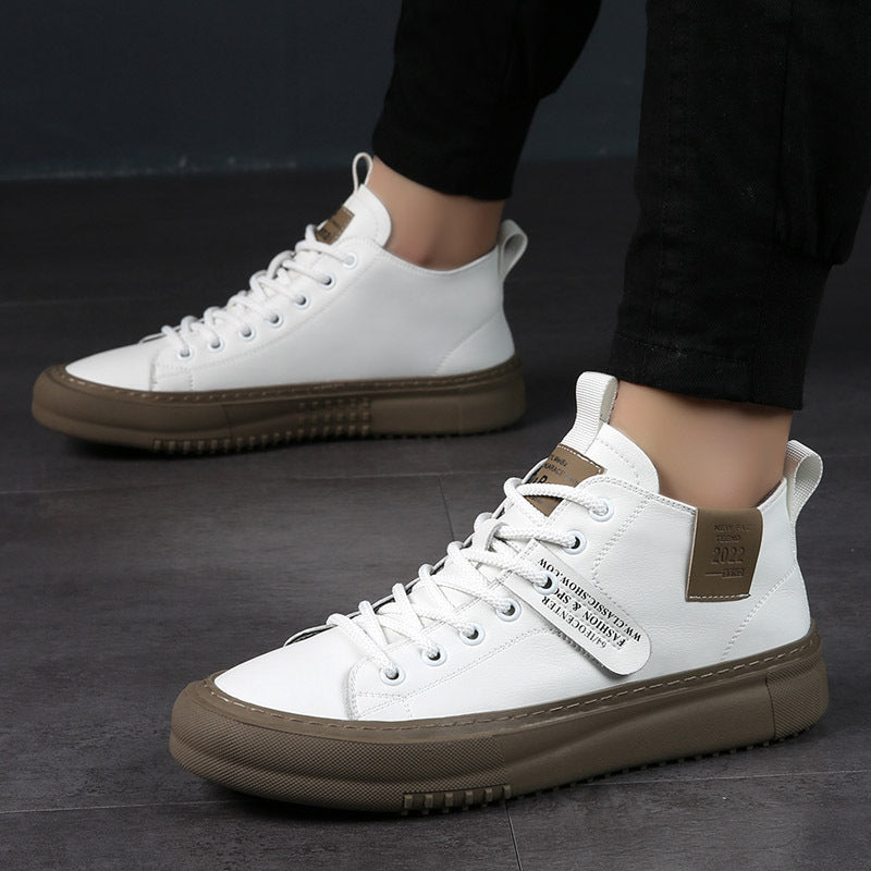 White high-top sneakers with brown soles and leather patches worn with black pants on dark floor